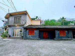 dom z czerwonymi drzwiami przed nim w obiekcie 霧台山豐民宿 w mieście Wutai