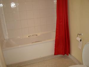 a bathroom with a white tub and a red shower curtain at Jolly Brewers Free House Inn in Bishops Stortford