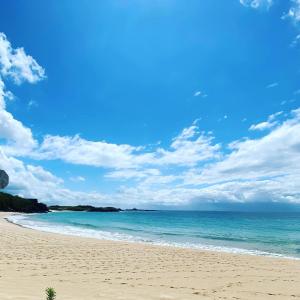 una spiaggia con l'oceano e un cielo e nuvole blu di ikibase Guest House a Iki