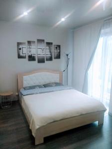 a bedroom with a white bed with pictures on the wall at Студия ЖК Лондон in Syktyvkar