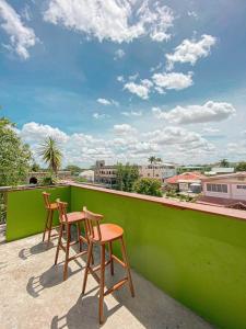 two chairs on a balcony with a green wall at Bella's Backpackers Cayo in San Ignacio