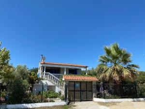 a house with a gate and a palm tree at Ikidiki Beach Villa in Ierissos