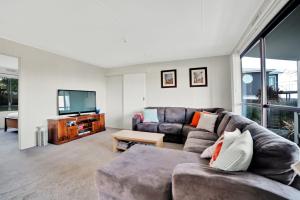 a living room with a couch and a flat screen tv at Dune Views in Bridport
