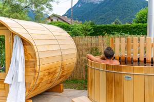 a man sitting in a hot tub in a backyard at Hygge Lodge Annecy in Doussard