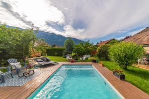 a backyard with a pool and a wooden deck with at Hygge Lodge Annecy in Doussard