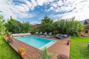 a backyard with a swimming pool and a wooden deck at Hygge Lodge Annecy in Doussard