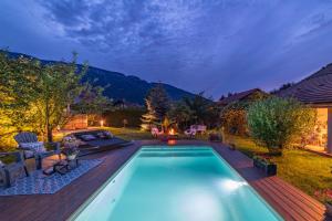 a swimming pool in a backyard with a wooden deck at Hygge Lodge Annecy in Doussard