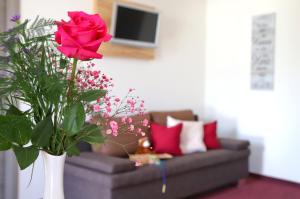 a living room with a couch and a vase with a red rose at Lohauserhof - Biohof und Hotel in Röhrmoos