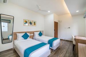 a hotel room with two beds and a mirror at SKYLA Studios & Suites - Hitech City in Hyderabad