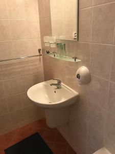La salle de bains est pourvue d'un lavabo blanc et d'un miroir. dans l'établissement Ubytovňa Gemini, à Stará Turá