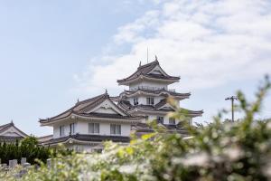 a tall white building with black roof at Tabist Yuasa Castle Onsen Hotel in Yuasa