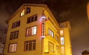 un edificio amarillo con un cartel en él por la noche en Hotel Mon Caprice, en Bucarest