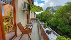 een balkon met een tafel en stoelen en een parasol bij Sunny Loft Kecskemét in Kecskemét