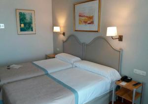 dwa łóżka w pokoju hotelowym z dwoma lampami w obiekcie Parador de Ceuta w mieście Ceuta