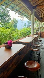 a bar with stools and a vase with flowers on it at Pondok Bamboo Sendangsari in Wonosobo