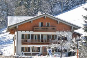 a large wooden house with a balcony in the snow at Fluchthäusl Ferienwohnung in Ramsau