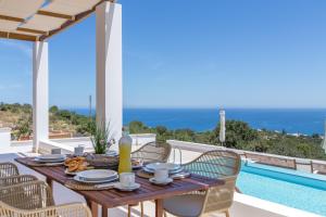 a dining table and chairs on a patio with a pool at Kallixeni Villas in Rethymno
