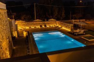 a swimming pool at night with chairs and umbrellas at Dimora Le Site in Torre Suda