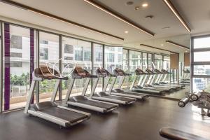 un gimnasio con filas de cintas de correr y ventanas en The Robertson Kuala Lumpur, en Kuala Lumpur