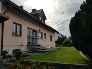 a white house with stairs and a grass yard at Ferienwohnung Landhausfeeling in Bad Abbach