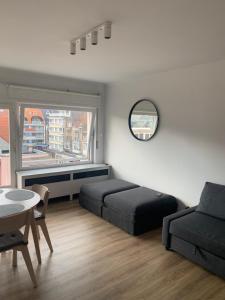 een slaapkamer met twee bedden, een tafel en een raam bij Les galets in Middelkerke