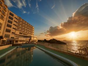 恩納村にあるHotel Miyuki Beachの海を背景にしたホテルのスイミングプール