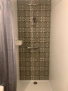 een badkamer met een douche en een tegelwand bij Les galets in Middelkerke