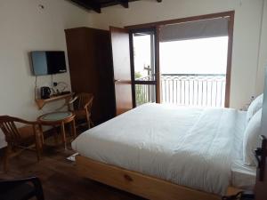a bedroom with a bed and a desk and a window at The Kumaon Retreat in Nainital