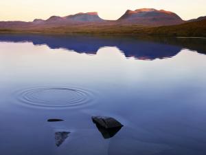 a rock in the middle of a lake at sunset at Hotell Fjället in Björkliden