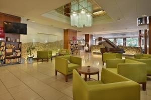 une salle d'attente avec des chaises vertes et un piano dans l'établissement Hotel Grand Litava Beroun, à Beroun