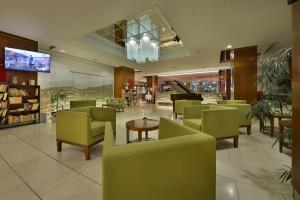 a restaurant with green chairs and a table and a piano at Hotel Grand Litava Beroun in Beroun