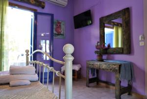 een paarse slaapkamer met een bed en een spiegel bij Antigoni Apartments in Parga