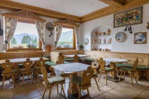 a dining room with tables and chairs and windows at Hotel Villa Argentina in Cortina dʼAmpezzo