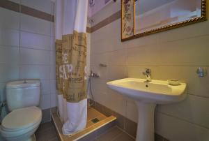 een badkamer met een wastafel, een toilet en een spiegel bij Antigoni Apartments in Parga +79 foto's