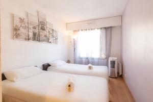 2 weiße Betten in einem Zimmer mit Fenster in der Unterkunft Quartier Vauban 2 bedroom apartment in Antibes