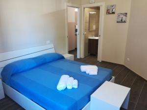 a blue bed with two pairs of towels on it at Scilla Upper Town in Scilla