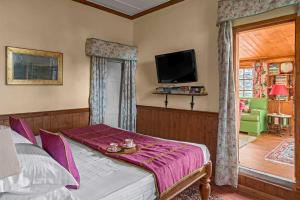 Schlafzimmer mit einem Bett mit lila Bettwäsche und einem TV in der Unterkunft StayVista at Sidhowal Lodge 1BR w Comp Breakfast in Shimla