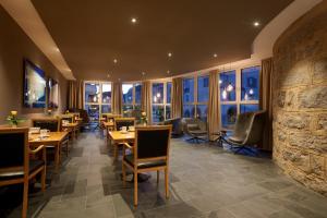 un restaurante con mesas y sillas de madera y ventanas en Hotel Goldene Rose, en Brunico