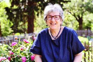 an older woman wearing glasses standing in front of flowers at Castel Campan in Bressanone