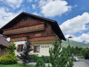 a wooden house with flowers on the top of it at Apartmány Villa Severka in Vysoke Tatry - Novy Smokovec