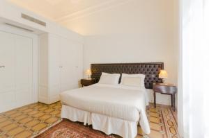 a white bedroom with a large bed with white sheets at Dimora Novecento in Pescara