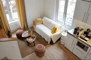 sala de estar con sofá blanco y 2 ventanas en La Cour du Vignoble en Kaysersberg