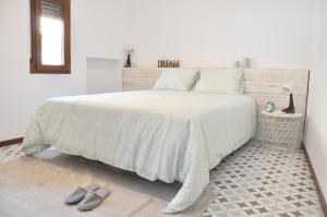 una camera da letto con un letto con piumone e scarpe bianche di Ca Tía Teresa a Denia