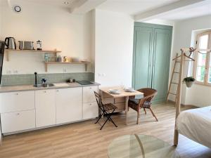a kitchen with white cabinets and a table and a desk at Carnets de voyage Coté studios in Lorgues