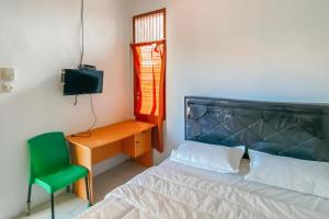 a bedroom with a bed and a desk and a green chair at RedDoorz Syariah near RS Harapan Bunda Banda Aceh in Geutieue
