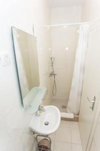 W białej łazience znajduje się umywalka i lustro. w obiekcie Apartments Palma Ragusa w Dubrowniku