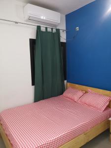 a bedroom with a bed with a blue wall and a green curtain at Sweet Home in Dakar
