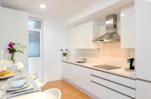 - une cuisine blanche avec des placards blancs et une table dans l'établissement Genteel Home Paseo de Reding, à Malaga