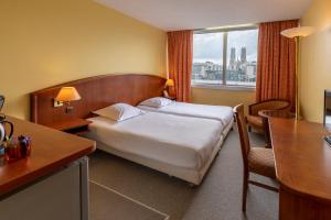 a hotel room with a bed and a desk and a window at The Originals Residence, Kosy Nancy Coeur de Ville in Nancy