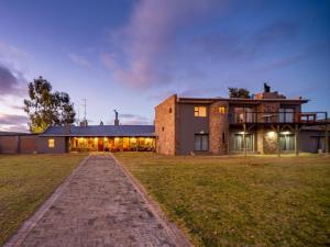 une grande maison en briques avec une pelouse devant elle dans l'établissement Kamagu Safari Lodge, à Touwsrivier